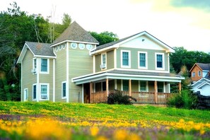 A two-story house with a porch and a tower-like structure.