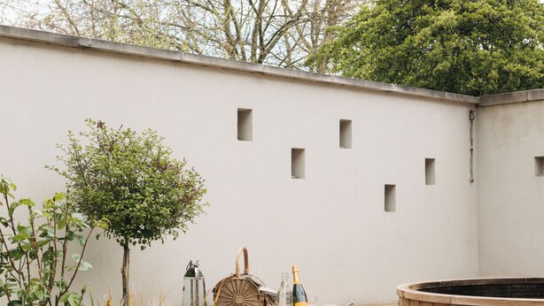 Un patio con un sofá de mimbre, un jacuzzi y una pequeña escalera que lleva a una terraza.
