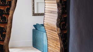 Una habitación con un arco de madera que conduce a una cama con almohadas azules, un espejo en la pared y un aparador.