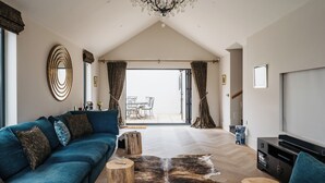 Un salón amplio con un sofá azul, una mesa de centro de madera y una lámpara de araña grande.