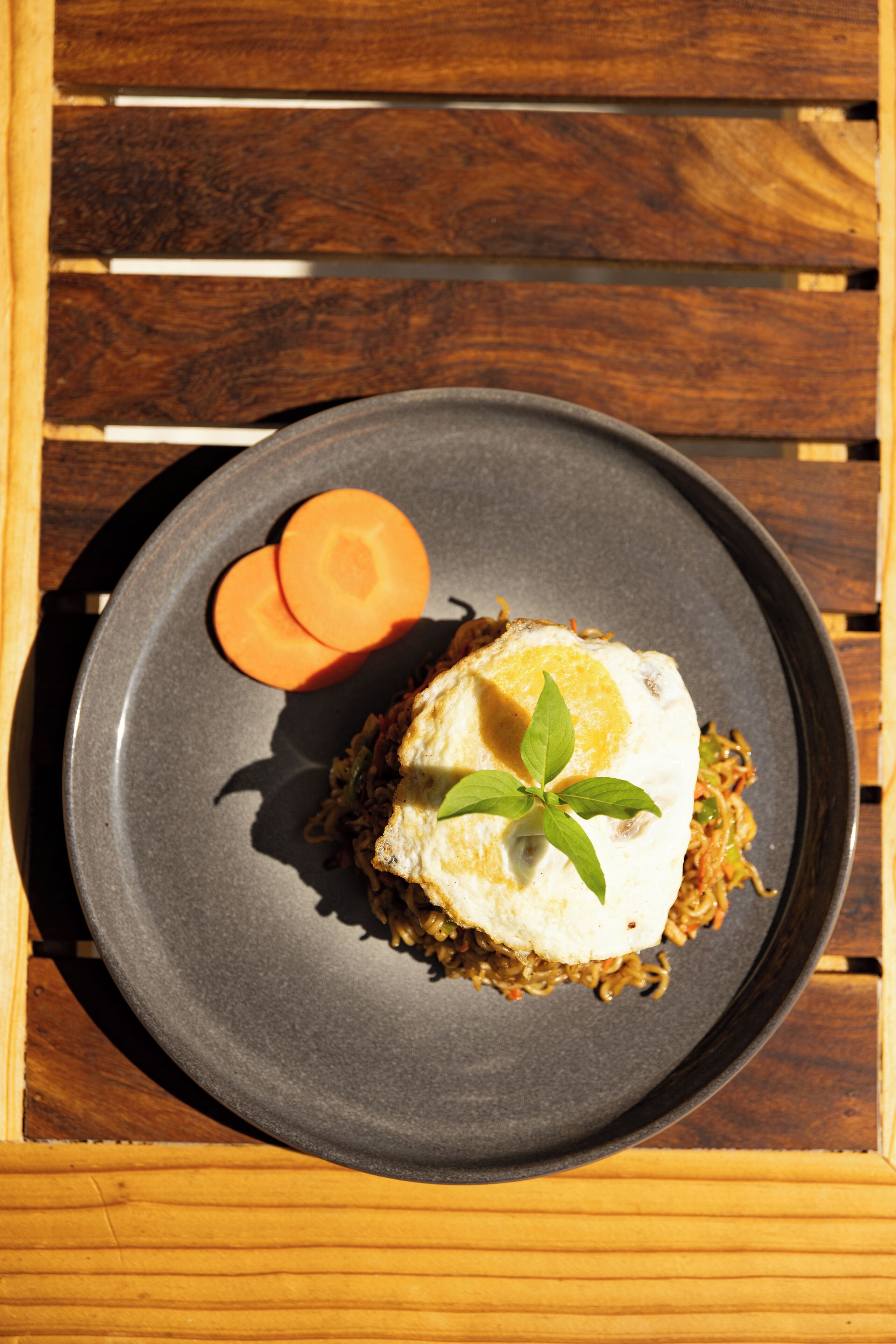 A plate with a dish, a carrot slice, and a basil leaf garnish.