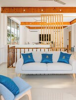 Una sala moderna con un sofá, una zona de comedor y una escalera de madera.