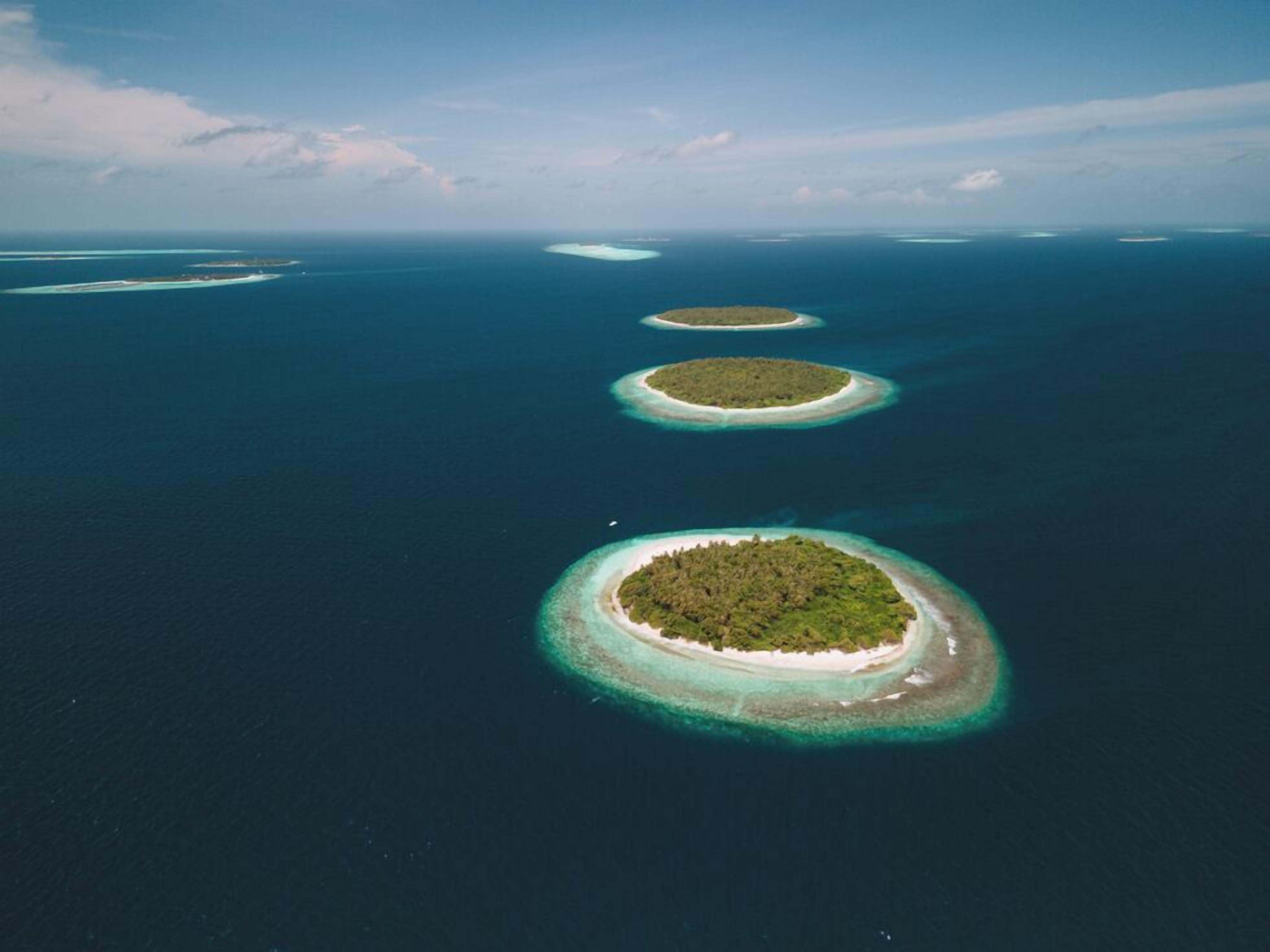 An aerial view of a chain of islands with clear blue waters and a clear sky.