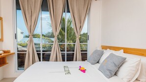 A hotel room with a large bed, a window with curtains, a wooden headboard, and a welcome sign on the bed. - Dhoani Maldives Guesthouse (Kendhoo)