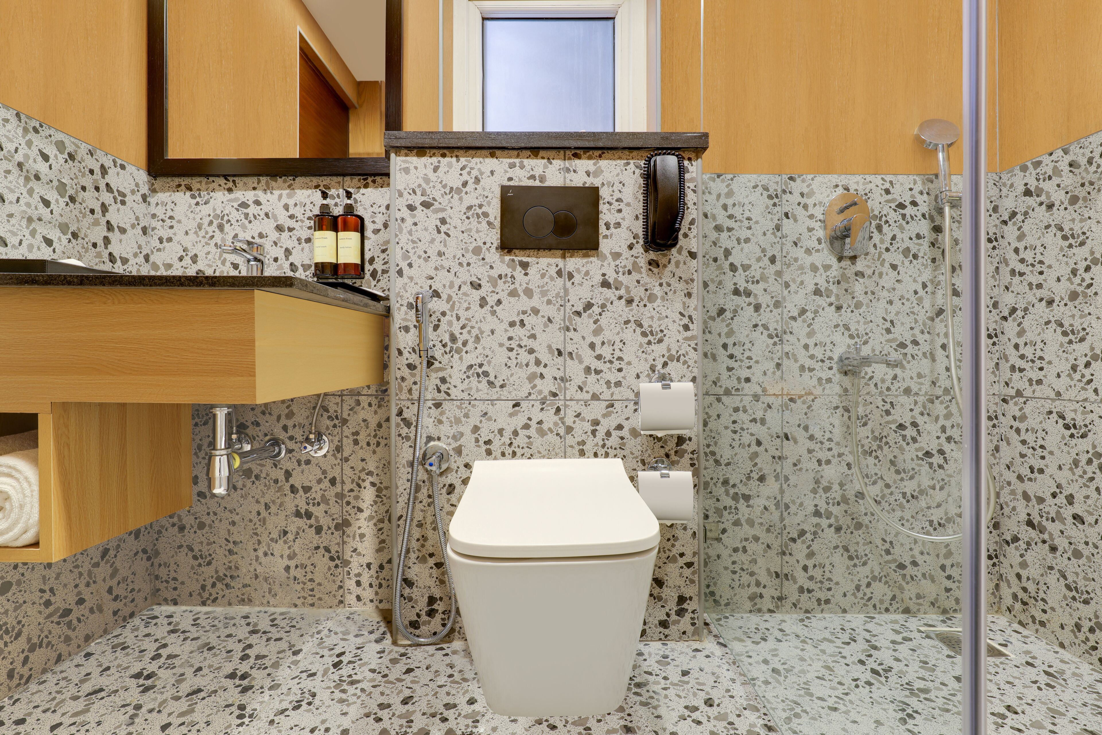 A bathroom with a white toilet, a sink with a marble countertop, and a shower area.