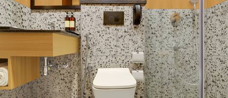 A bathroom with a white toilet, a sink with a marble countertop, and a shower area.