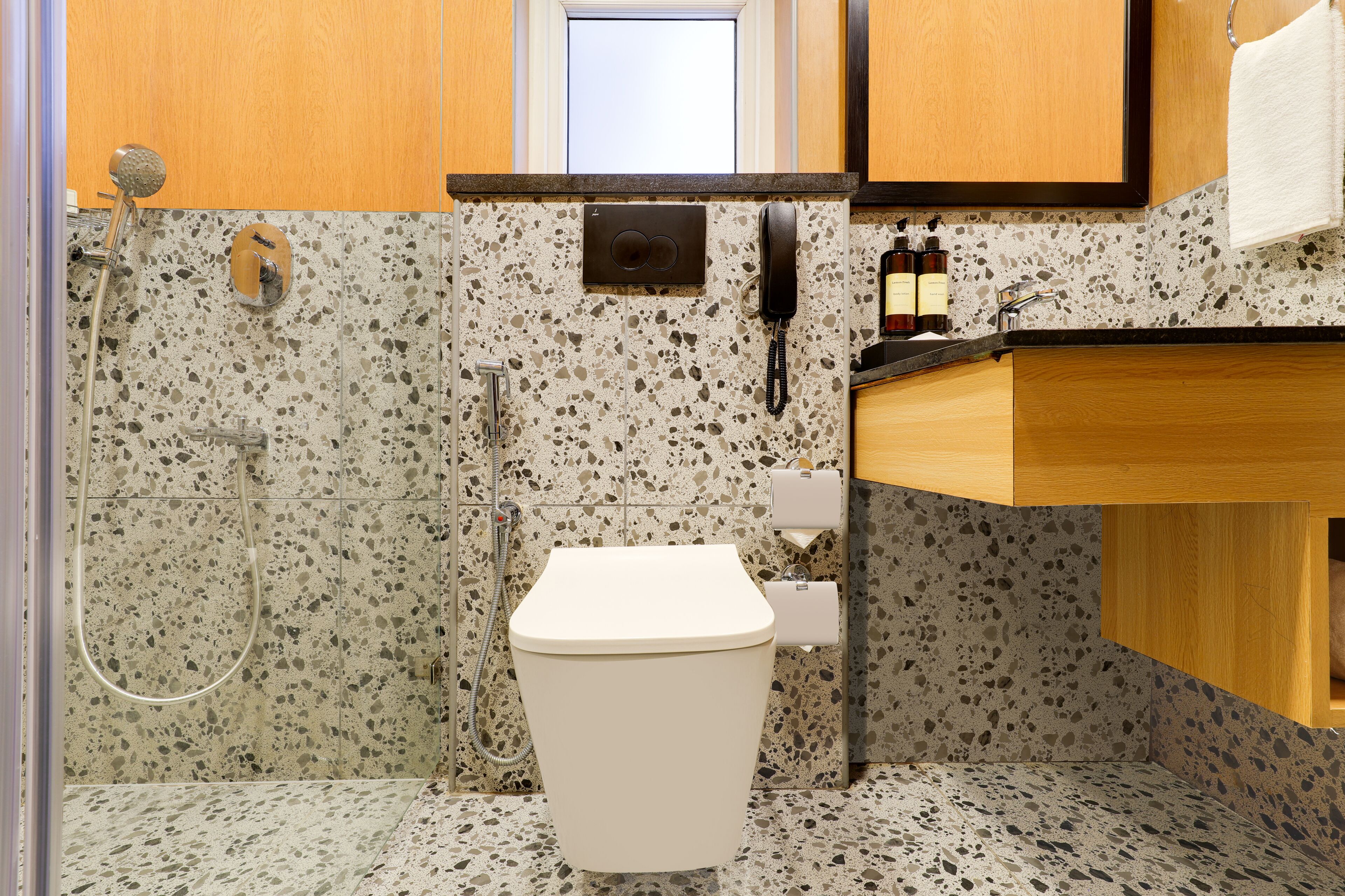 A bathroom with a toilet, shower, and a phone mounted on the wall.