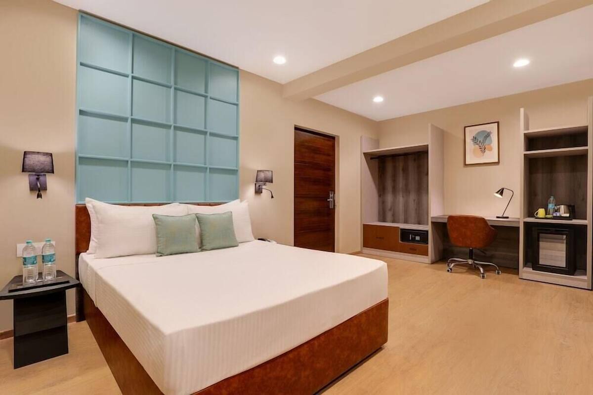 A hotel room with a large bed, bedside tables, a desk, and a wardrobe.
