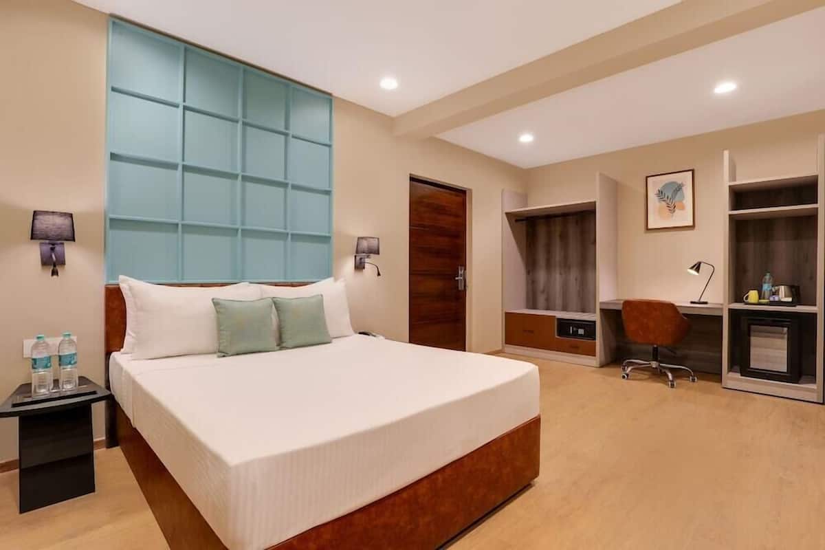 Una habitación de hotel con una cama grande, mesitas de noche, un escritorio y un armario.