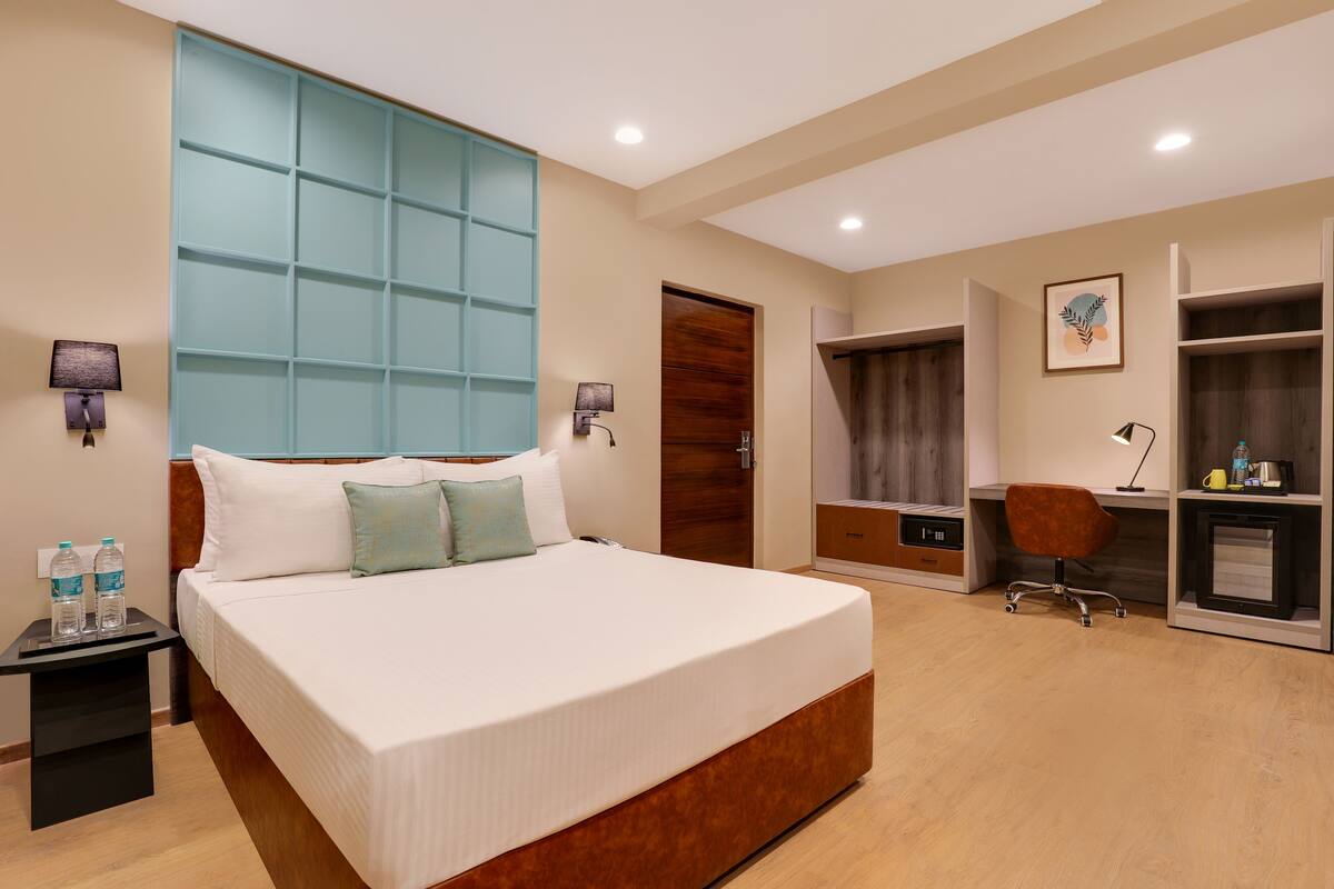 A hotel room with a large bed, a desk, a wardrobe, and a bathroom.