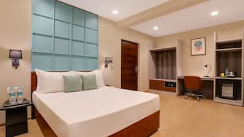Habitación de hotel con una cama grande, un escritorio, un armario y un baño.