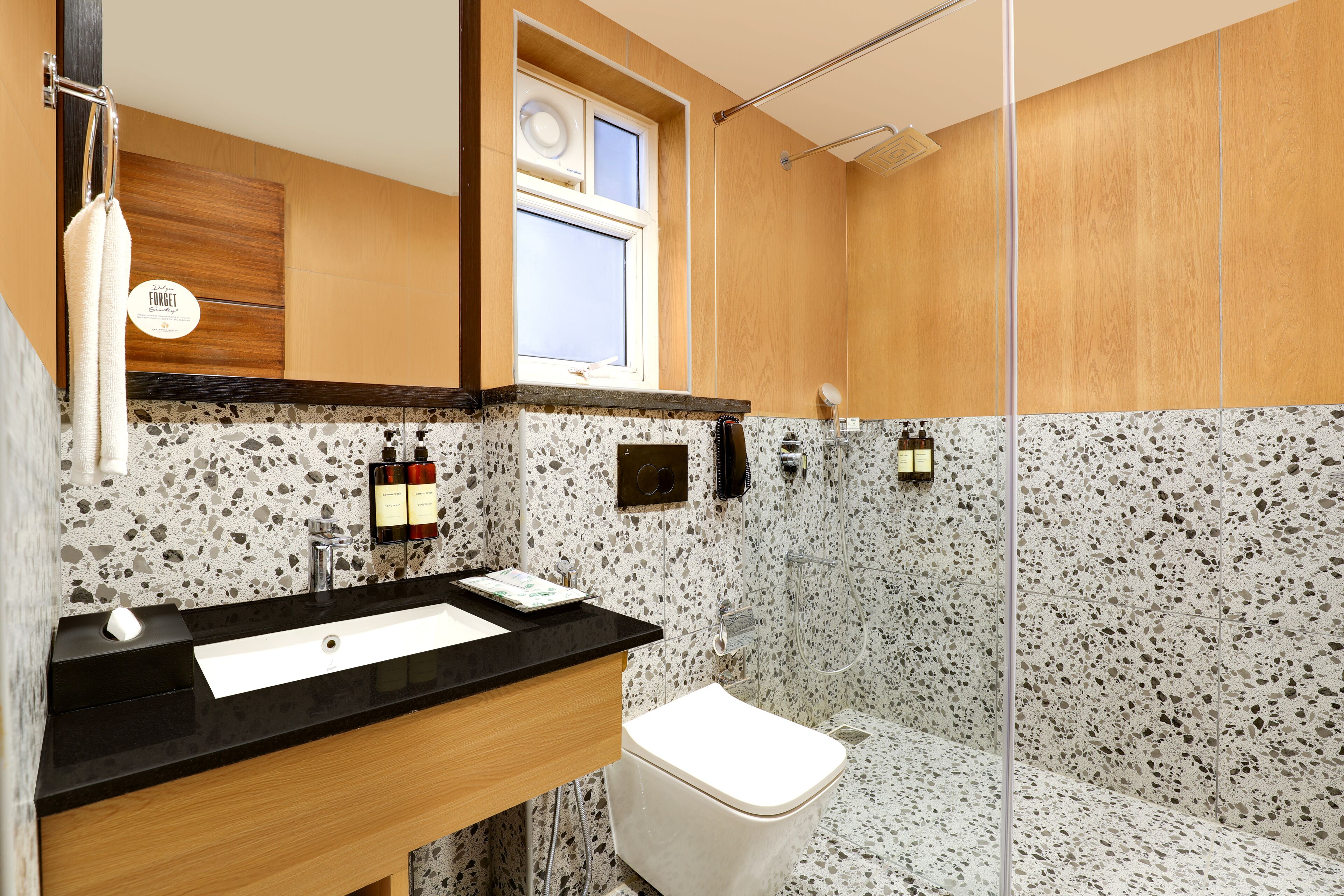 A modern bathroom with a granite countertop sink, a white toilet, and a shower area.