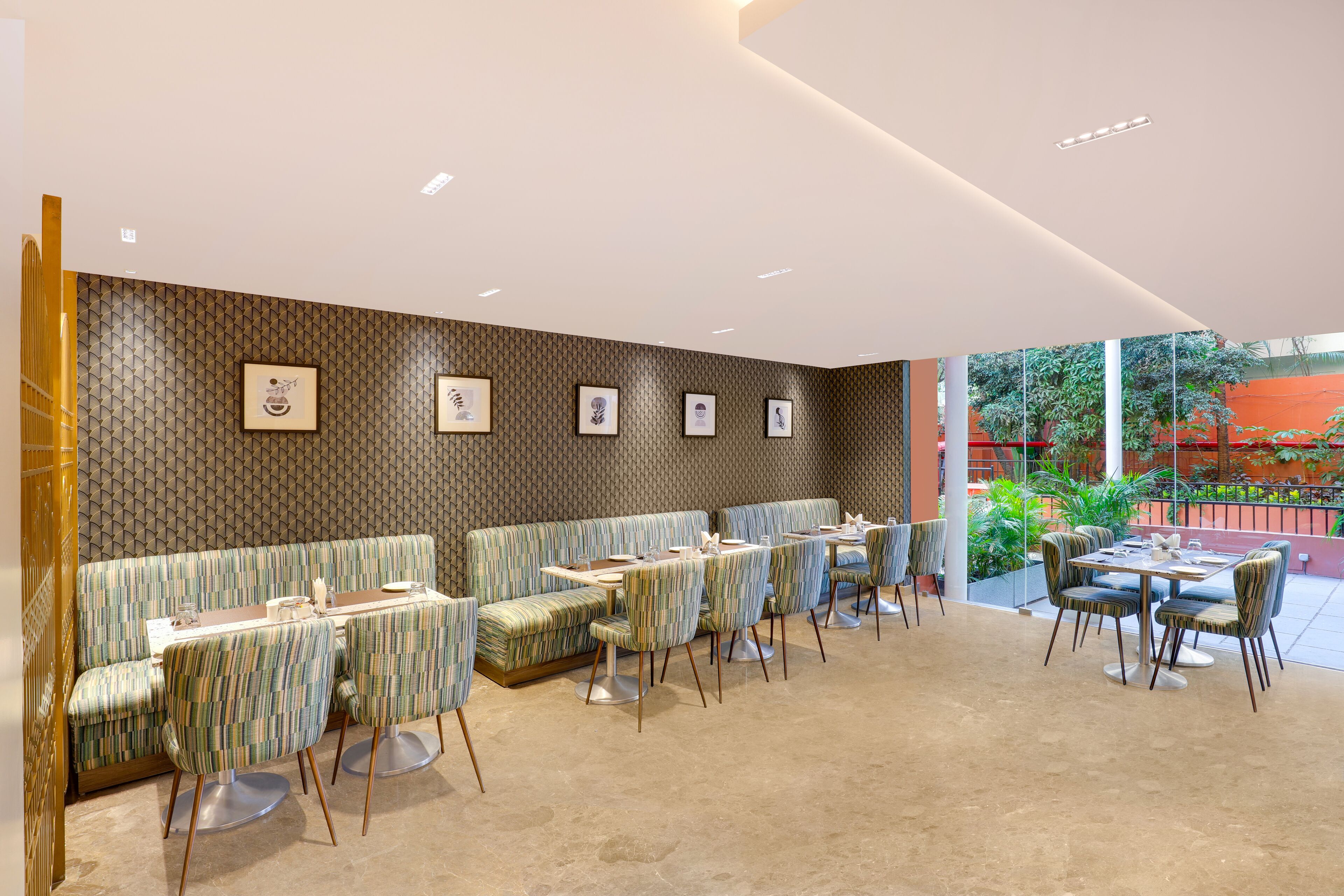 Un restaurant moderne avec un mur décoré de motifs, des sièges rembourrés et une vue sur l’extérieur.