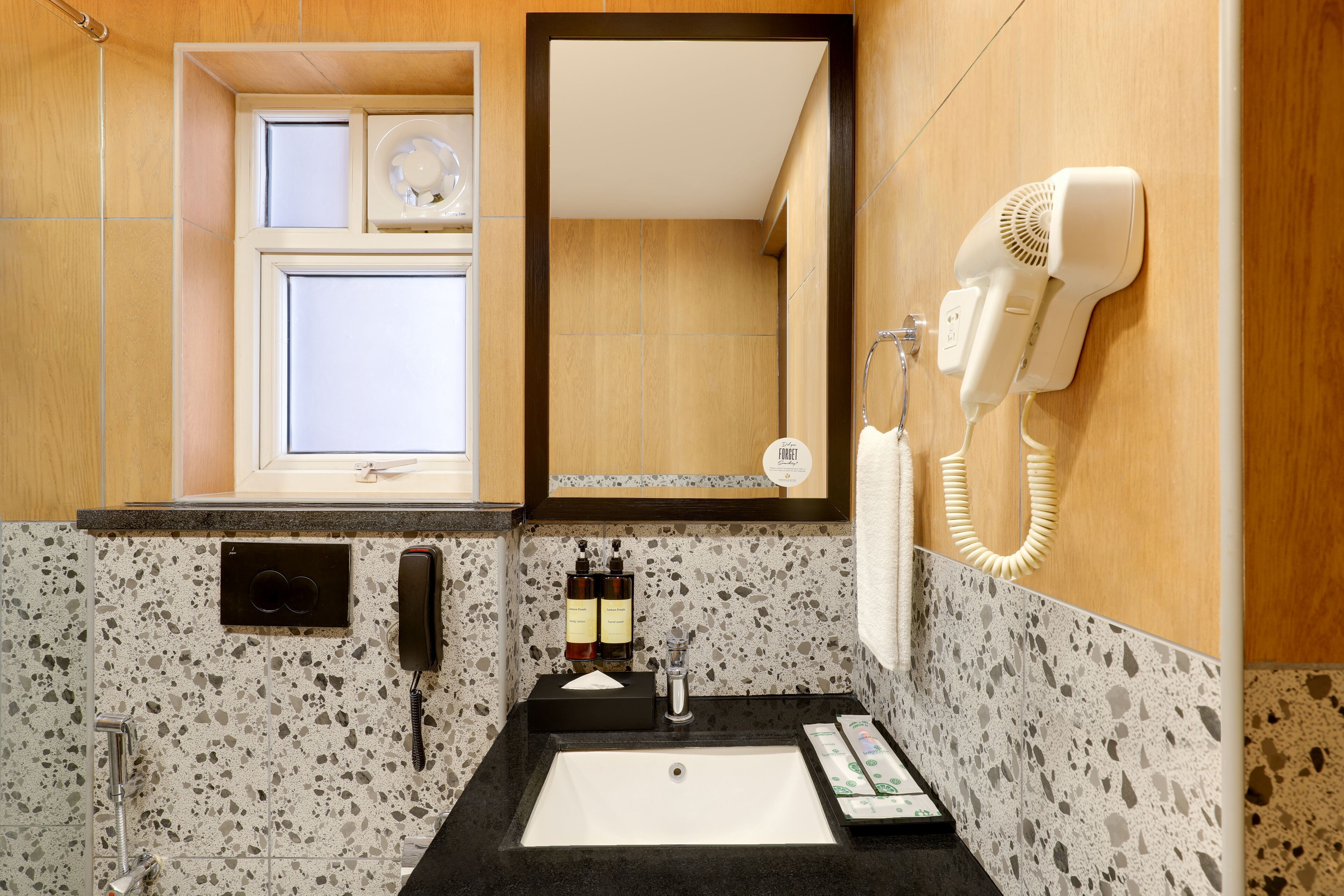 A bathroom with a sink, mirror, hairdryer, and toiletries.