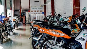 A motorcycle showroom with several motorcycles on display, a ceiling fan, and a sign in the background. - The Dorm Tam Toà (Dong Hoi)