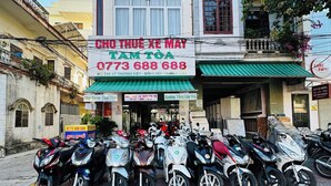 A building with a sign for 'The Dorm Tam Toa' and a row of parked scooters in front. - The Dorm Tam Toà (Dong Hoi)