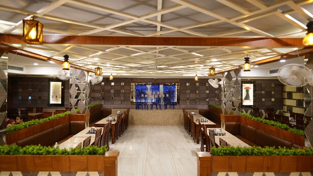 A spacious restaurant with a central bar, booths, and a high ceiling with geometric patterns. - Golden Hut Derabassi (Dera Bassi)