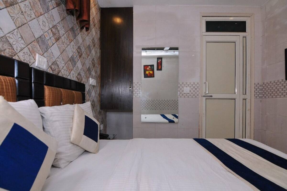 Une chambre d’hôtel avec un lit, une tête de lit, une armoire, un miroir et une porte.