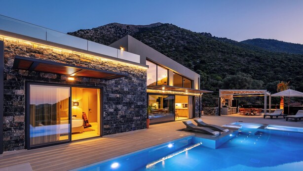 Eine moderne Villa mit Swimmingpool, Steinhausfassade und Blick auf eine gebirgige Landschaft.