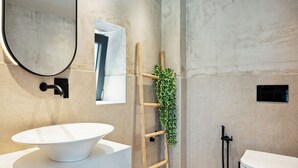 Ein Badezimmer mit einem weißen Waschbecken, einem Spiegel, einer Holzleiter und einer grünen Pflanze.