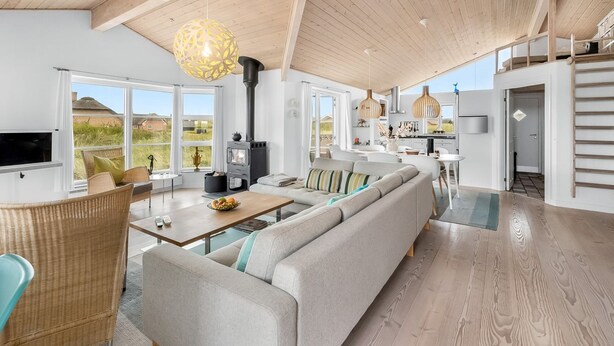 A spacious living area with a large sofa, dining table, and a kitchen in the background. - "Elfi" - 700m from the sea by Interhome (Ringkøbing)