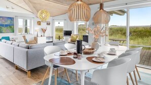 A modern living room with a large sofa, a dining table, and two pendant lights. - "Elfi" - 700m from the sea by Interhome (Ringkøbing)
