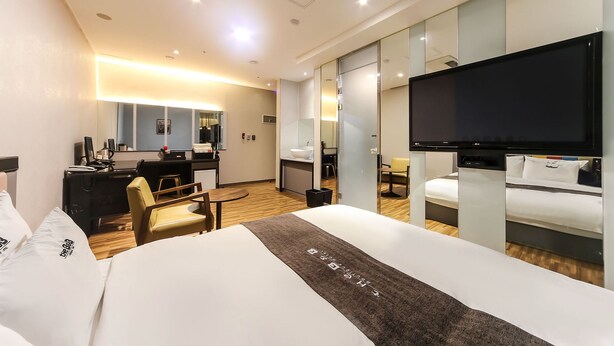 Una habitación de hotel con cama, escritorio, silla, televisor y baño.