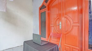 Una habitació amb un ordinador portàtil sobre una taula, una porta vermella i una cadira vermella.