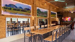 A restaurant with long wooden tables and chairs, large windows, and a television screen. - Tam Coc Cat Luong Homestay (Nam Hoa Lu)
