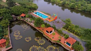 A riverside hotel with a swimming pool, inflatable slides, and several small structures along the water. - Tam Coc Cat Luong Homestay (Nam Hoa Lu)