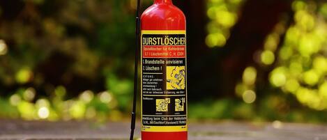 A red fire extinguisher with a black nozzle and a yellow label.