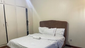 Una cama bien hecha con sábanas blancas, un cabecero marrón y una almohada blanca.