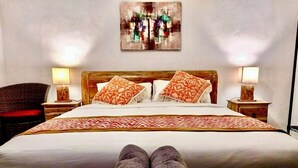 A neatly made bed with patterned pillows, a wooden headboard, and two bedside lamps. - Gopala Villa North Ubud (Ubud)