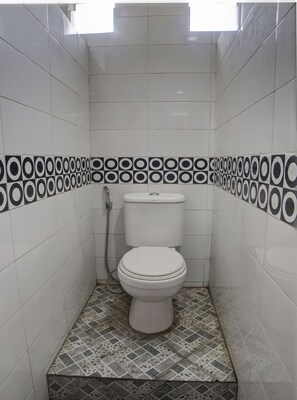 A small, clean bathroom with a toilet, a shower, and a tiled floor. - Hotel O Finest House Near Amplas Bus Terminal (Medan)