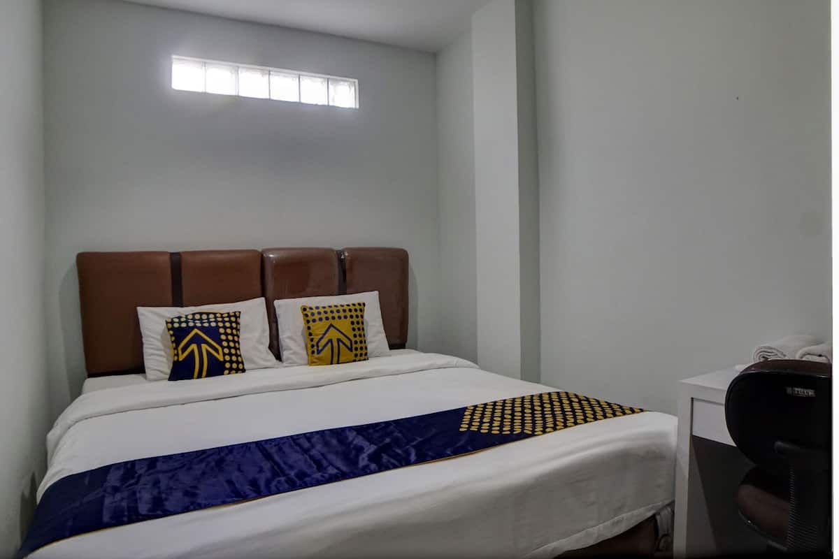 A hotel room with a bed, a desk, and a chair.