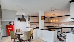 Una cocina moderna con una isla central, luces colgantes y un comedor con sillas y una mesa.