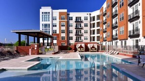 A modern apartment building with a swimming pool, outdoor seating, and a covered area. - 100 Year-old Historic Brick 2BR Loft Large Patio2 (Durham)
