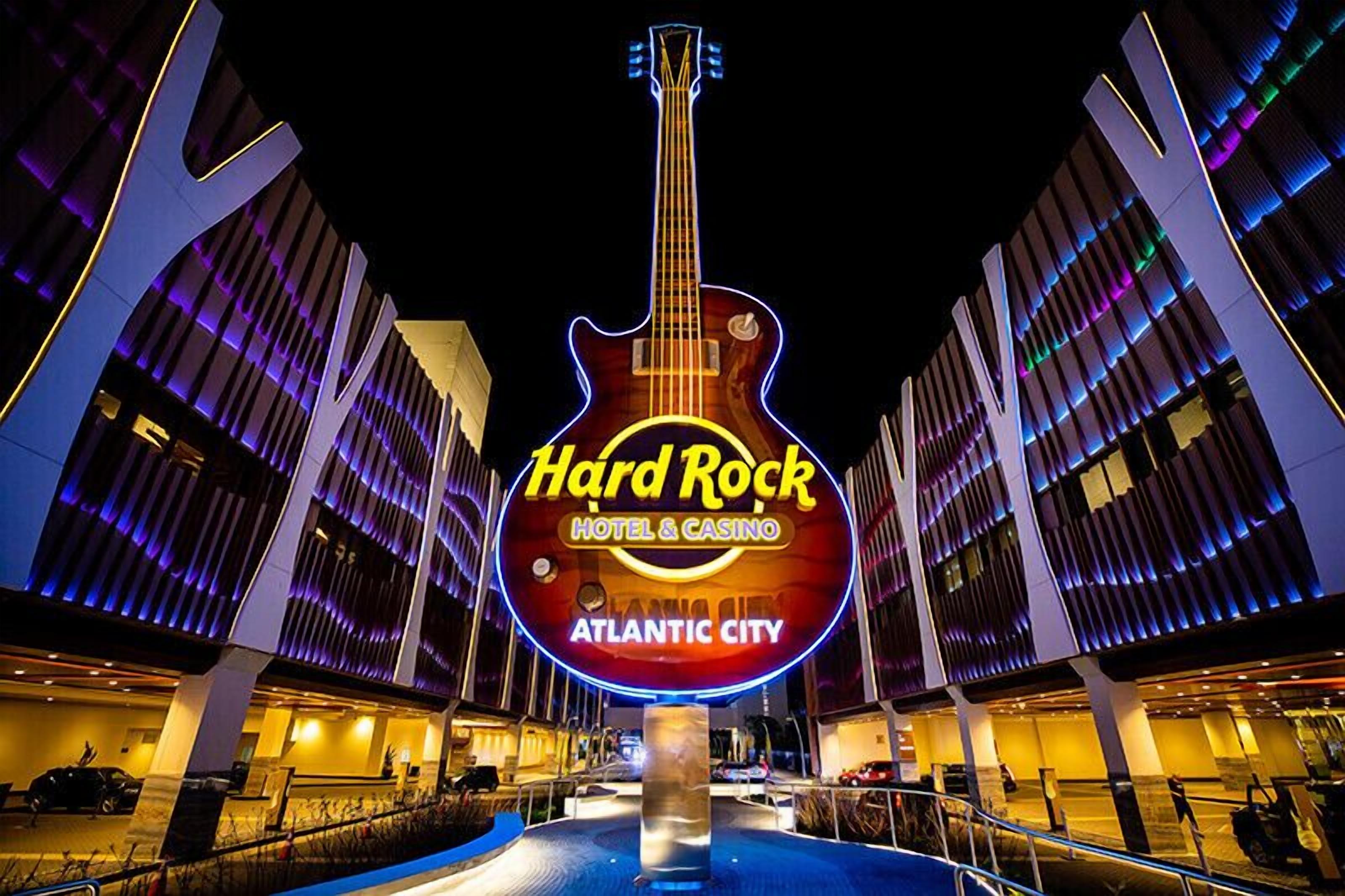 Ein Hard Rock Hotel & Casino mit einem auffälligen, gitarrenförmigen Neonzeichen, moderner Architektur und einem Poolbereich.