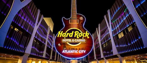 A Hard Rock Hotel & Casino with a prominent guitar-shaped neon sign, modern architecture, and a pool area.