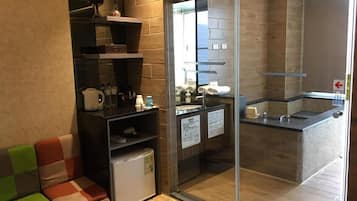 A modern bathroom with a glass shower enclosure, a sink, and a small refrigerator.