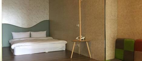 Un dormitorio con una cama, un perchero de madera y un sofá verde y rojo.