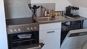 A compact kitchen with a built-in oven, a dishwasher, and a sink. - Gemütliche Wohnung im Nationalpark Eifel mit Outdoor Wellnessbereich (Mechernich)