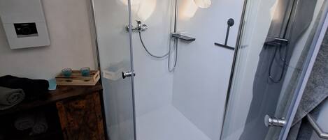 A modern bathroom with a glass-enclosed shower, a wooden vanity, and a towel rack.