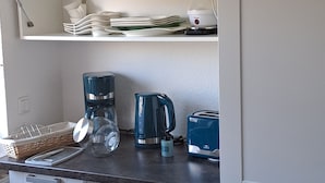 A kitchen with white cabinets, a coffee maker, a kettle, and a toaster on the counter. - Gemütliche Wohnung im Nationalpark Eifel mit Outdoor Wellnessbereich (Mechernich)