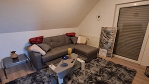 A modern living room with a grey sectional sofa, a small coffee table, and a fluffy grey rug. - Gemütliche Wohnung im Nationalpark Eifel mit Outdoor Wellnessbereich (Mechernich)