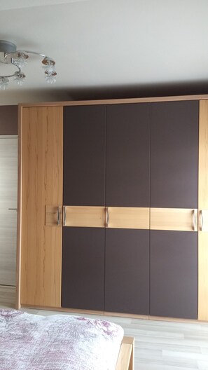 Ein Schlafzimmer mit großem Kleiderschrank, einem Bett und einer Deckenleuchte.