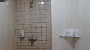 A bathroom with a shower, toilet, and a shelf with toiletries.