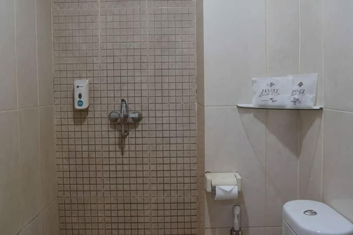 A bathroom with a tiled wall, a toilet, a paper towel dispenser, and a soap dispenser.