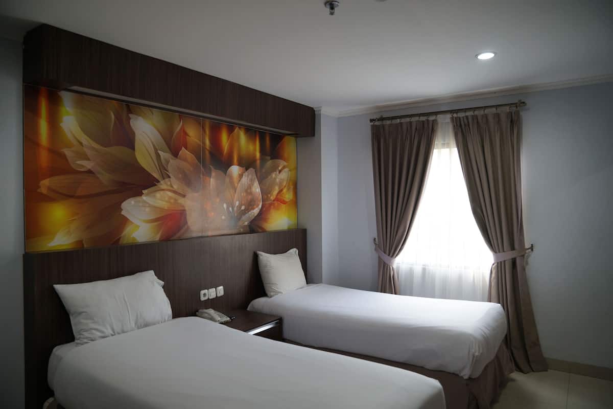 Habitación de hotel con dos camas, un cuadro floral grande en la pared y una ventana con cortinas.
