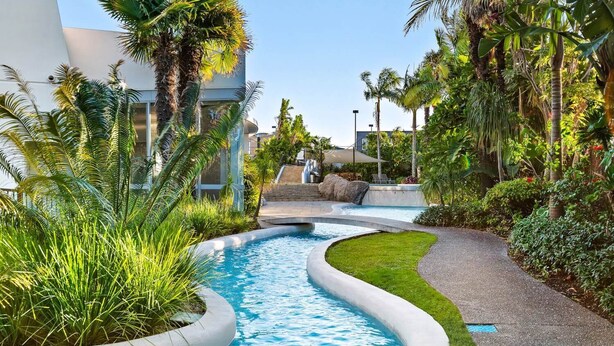 Una piscina de diseño curvo, rodeada de abundante vegetación y palmeras.